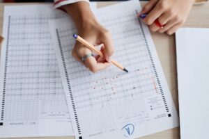 Top view closeup of teenage girl doing tests with A grade over table, copy space