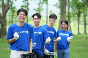 A group of high school volunteers pick up trash on the lawn after an outdoor activity.