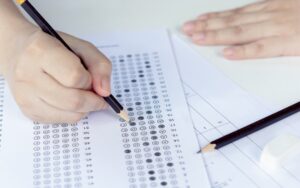 Student taking SAT test for college using pencil and filling in multiple choice answers on a scantron test sheet