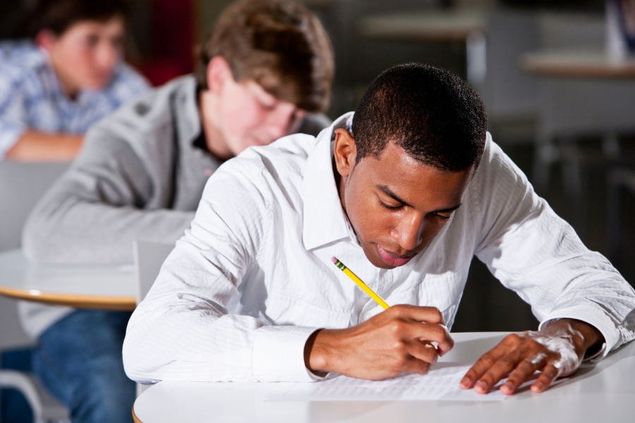 A focused high school student taking a standardized test, symbolizing the debate over submitting SAT or ACT scores to test-optional colleges.