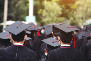 Graduating students in caps and gowns at a commencement ceremony, symbolizing college debt and financial planning.