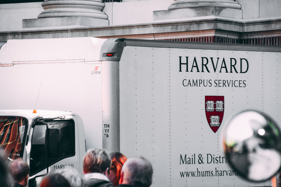 Harvard Campus Services truck parked in front of a university building, symbolizing financial operations at top colleges.