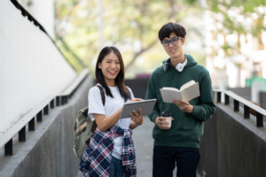 Two international students smiling and studying outdoors on a U.S. college campus.