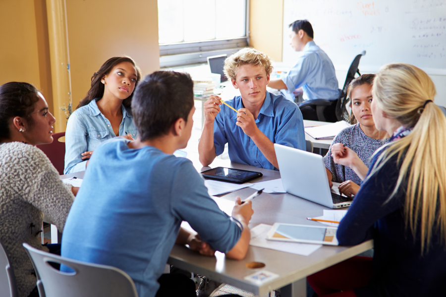 A group of high school students in a classroom engaged in discussion, representing students preparing for AP classes and exams.