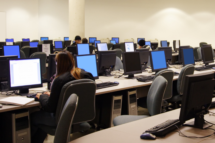 A group of high school students in a computer lab with desktop computers taking the digital SAT under new adaptive testing models