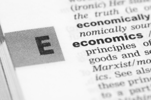 A close-up of a dictionary page highlighting the word "economics," representing academic research and publication in the field.